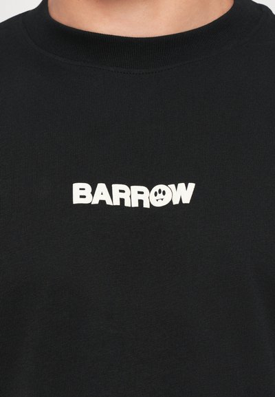 Maglietta nera a girocollo con la scritta bianca "BARROW", che presenta un faccina triste all'interno della lettera "O" sul petto.
