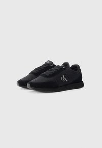 Zwarte sportieve schoenen van een mix van textiel en suede, met een platte rubberen zool en zilveren logo-accenten aan de zijkant en op de tong.