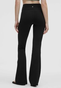 Svarta utsvängda leggings med hög midja. Tillverkade av elastiskt tyg, med en slät yta och subtil logotypdetalj på baksidan.