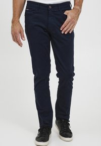 Chinos bleu marine en coton avec une coupe slim, dotés de poches avant et arrière, d'une fermeture à bouton et d'un accent de marque subtil.