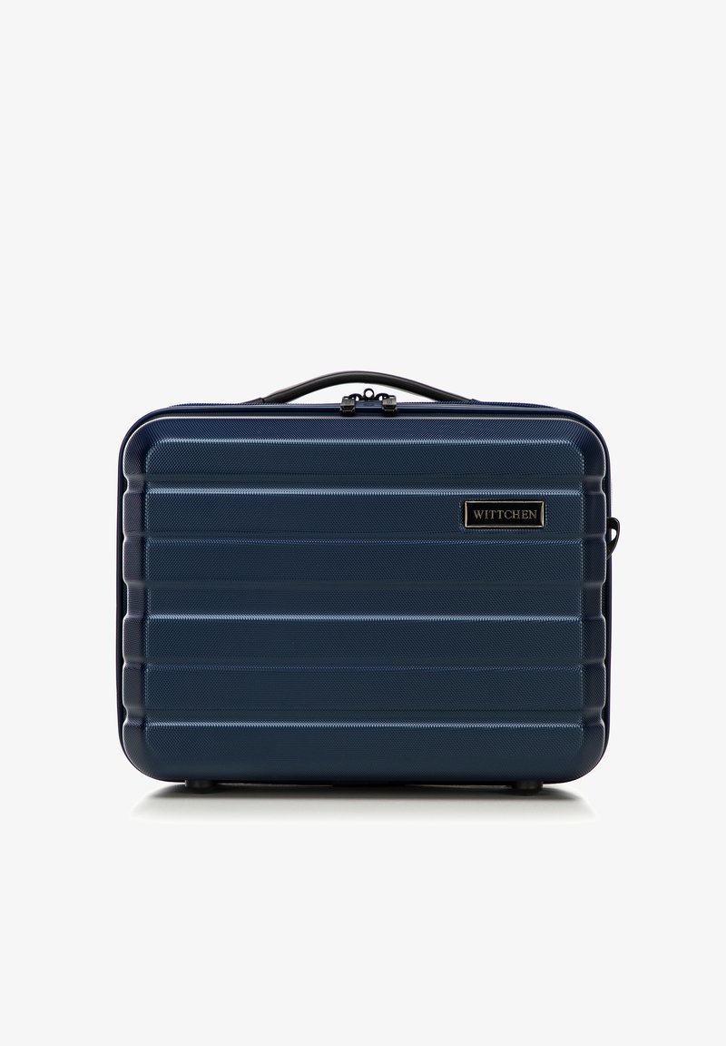 Marineblauwe harde koffer met horizontale ribbels, zwarte accenten en een handvat aan de bovenkant. Heeft een merklogo plaat aan de voorkant.