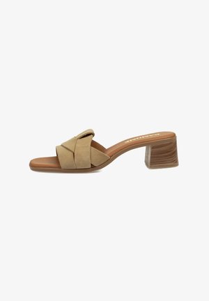 Sandalia de tacón beige con un diseño de tiras cruzadas, con un tacón bloque moderado y una plantilla marrón, sobre un fondo blanco liso.