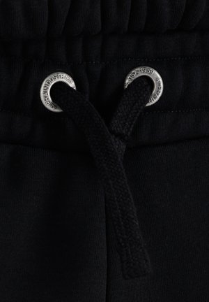 Black sweatpants waistband with a textured elastic band and silver grommets. Features a black drawstring for adjustment.