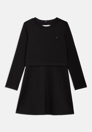 Μαύρο φόρεμα με μακριά μανίκια από βαμβάκι, με εφαρμοστό τούλι, φαρδύ τελείωμα και κλειστό λαιμόκοψη με μικρό λογότυπο στο στήθος.