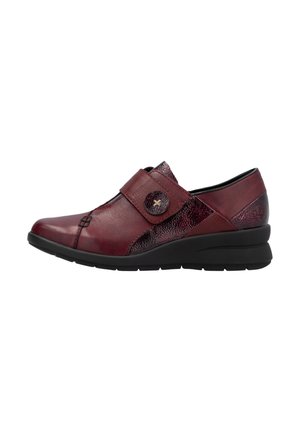 Chaussure en cuir rouge avec un accent texturé, bout arrondi et sangle à crochet et loop. Elle dispose d'une semelle en biais basse pour un confort supplémentaire.