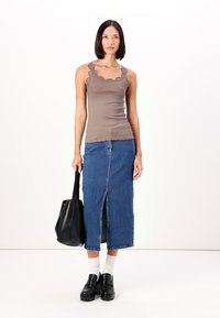 Débardeur marron à côtes avec dentelle, associé à une jupe midi en denim bleu dotée d'une fente à l'avant. Sac à main noir et chaussures à plateforme.
