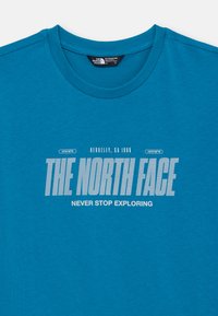 Turkio medvilnės T-maišelis su apvaliu kaklu. Priekinis spaudinys rodo "THE NORTH FACE" sodria balta spalva su užrašu "NEVER STOP EXPLORING" žemiau.