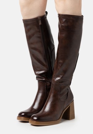 Botas de cuero marrón hasta la rodilla con un tacón de madera grueso, que presentan un cierre lateral y una textura suave. Diseño de pantorrilla ancha para un ajuste cómodo.