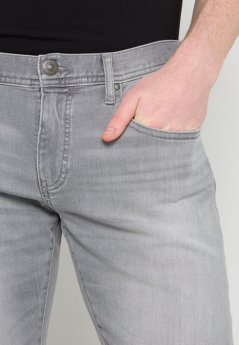 Szare dżinsy w wąskim kroju, z przednią kieszenią, zapięciem na guzik oraz przeszyciami wzdłuż szwów.