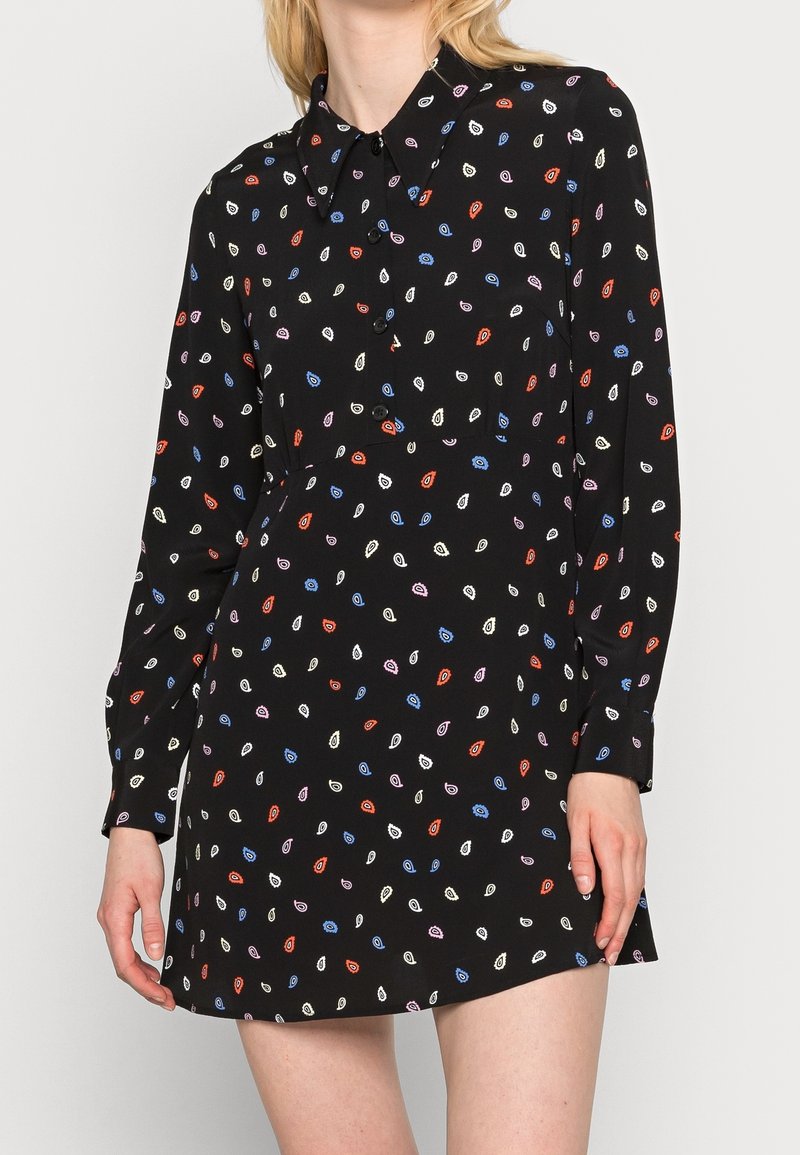 Czarna sukienka koszulowa z kołnierzykiem i długimi rękawami, ozdobiona małymi, kolorowymi wzorami liści. Miękka tkanina o luźnym kroju.