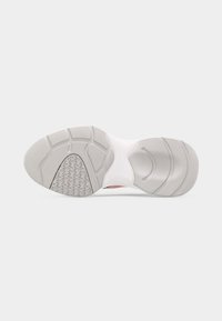 Σόλα λευκού και γκρι αθλητικού παπουτσιού με διακοσμημένο πέλμα και χωρισμένες περιοχές πρόσφυσης σε απλό ανοιχτό φόντο.