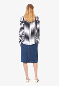 Camicia a righe a maniche lunghe blu navy e bianca, abbinata a una gonna di jeans lunga fino al ginocchio. Tessuto morbido con una vestibilità casual, con orlo arrotondato.