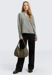 Grey patterned knit top with a V-neck, paired with black wide-leg pants. The model holds a green suede shoulder bag, wearing black chunky boots.