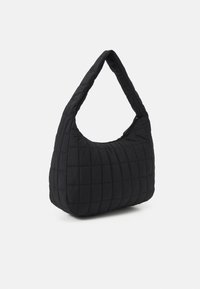 Sac à main noir matelassé avec une bandoulière unique incurvée et une forme arrondie, présentant une texture douce et un détail de couture subtil.