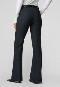 Mørkeblå skræddersyede bukser med en udvidet benlængde, lavet af tekstureret stof, med en tætsiddende taljebånd og baglommer.