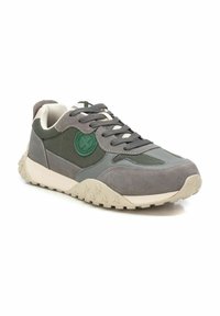 Zapatilla gris que combina materiales de ante y malla, suela de goma texturizada, logotipo de acento verde y cierre de cordones.