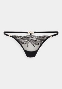 String preto com parte de trás em renda transparente, apresentando um design de samambaia bordado. Acentuado com detalhes em metal dourado e alças elásticas finas.