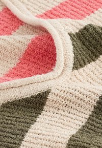 Patterned blanket featuring alternating stripes of pink, green, and beige. Material has a textured, plush finish with a soft, cozy appearance.