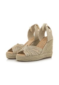 Sandales compensées beiges avec un design tissé complexe sur le dessus, comportant un dos en tissu texturé et un talon enroulé de jute.