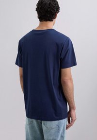 Camiseta de algodón azul marino con cuello redondo, mangas cortas y un ajuste relajado. Diseño liso, textura suave, sin patrones ni acentos visibles.