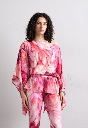 Outfit con motivo floreale composto da una maglietta ampia, a spalle scoperte, e leggings coordinati, nelle tonalità di rosa, rosso e crema.
