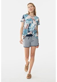 Korte mouwen overhemd met een blauw, roze en wit bladpatroon, gecombineerd met marineblauwe en witte gestreepte shorts; geweven beige sandalen.