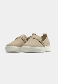 Tan canvas slip-on shoes with a braided accent across the top, featuring a textured white rubber sole and minimalistic design.