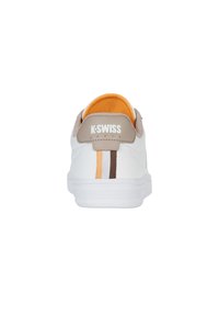 Weisses Sneaker mit einer beige Fersenkappe, orangefarbenem Innenfutter und braunen, orangefarbenen sowie weißen Akzentstreifen auf der Rückseite. Markenlogo auf der Ferse.