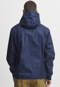 Marinevannjakke med snorhette, elastiske mansjetter og diverse hem. Glatt tekstur, holdbart materiale og minimalistisk design.