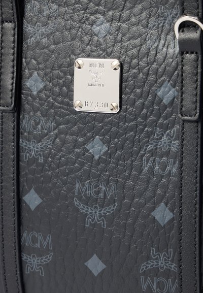 Schwarze, strukturierte Lederhandtasche mit grauen MCM-Logos und einer silbernen Metallplatte, die "MCM München" und den Code "B7330" eingeprägt hat.