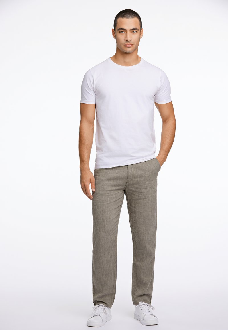 T-shirt blanc à manches courtes associé à un pantalon rayé gris clair et des baskets blanches. La tenue présente un design simple et décontracté, axé sur le confort.