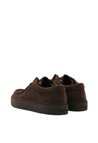 Scarpe basse in suede marrone con punta arrotondata, design minimalista e suola in gomma. Presentano il marchio Calvin Klein sul tallone.
