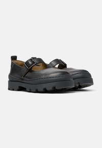 Zapatos de cuero negros con punta redonda, que cuentan con dos correas ajustables, una suela de goma negra gruesa y detalles de costura mínimos.