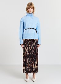 Helles blaugraues, grob gestricktes Rollkragensweá mit geripptem Saum, kombiniert mit einem Midi-Rock im braun-schwarzen Leopardenmuster und weißen spitzen Absatzschuhen.