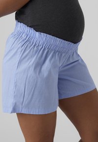 Shorts rayés bleu clair avec une taille élastique, présentant une coupe décontractée et un tissu léger adapté pour le confort.