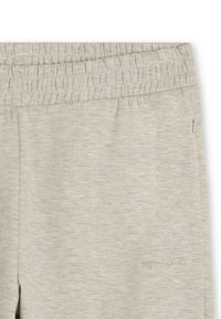 Pantalones de chándal gris claro con cintura elástica, hechos de una tela suave. Presentan un pequeño logo en relieve y un bolsillo lateral con cremallera.
