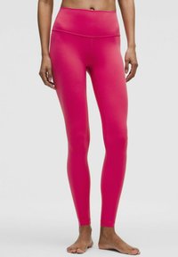 Aansluitende roze leggings met een hoge tailleband, gemaakt van een gladde, elastische stof. Beschikt over geen zichtbare naden en een slanke, gestroomlijnde uitstraling.