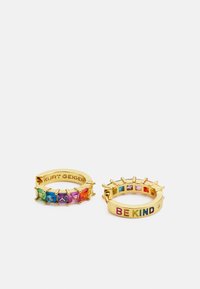 Gouden ringen met kleurrijke cubic zirconia stenen. Eén heeft de opdruk "KURT GEIGER", de ander leest "BE KIND" in meerkleurige letters.