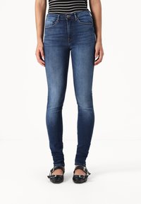 Tanke jeans v temno modrem denimu z gladko teksturo, z srednje visokim pasom, sprednjimi žepi in zapiranjem na en gumb.