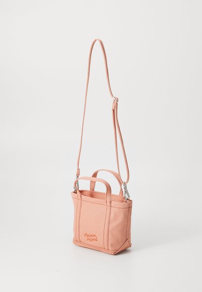 Bolso de lona rosa con dos asas cortas y una correa de hombro desmontable. Presenta una forma rectangular y un logo bordado en la parte frontal.