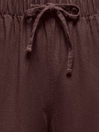 Pantalon en tissu marron foncé avec une taille élastique et un cordon de serrage noué au centre devant.