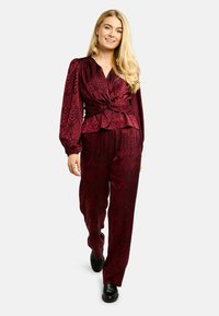 Bordový dvojdielny outfit s textúrovaným hadím vzorom. Topy majú zavinovací dizajn a balónové rukávy, doplnené voľnými nohavicami.