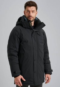 Zwarte geïsoleerde parka met een capuchon, rits- en drukknoopsluitingen, zijzakken en een slanke, gladde buitenkant. Beschikt over een contrasterende binnenvoering.