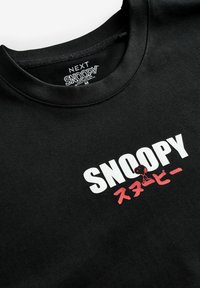 Sort bomulds sweatshirt med hvid og rød "SNOOPY" tekst samt grafik af Snoopy, rund halsudskæring og ribbet tekstur.
