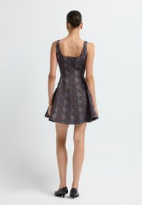 Robe patin floue marron à motif avec un décolleté carré et des bretelles larges, présentant une jupe évasée et un tissu texturé. Talons noirs.