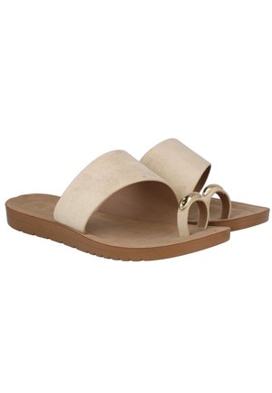 Sandalias planas beige con una amplia tira frontal y una banda para el dedo con detalle de anillo metálico dorado, y suela marrón con un ligero patrón de la banda de rodadura.
