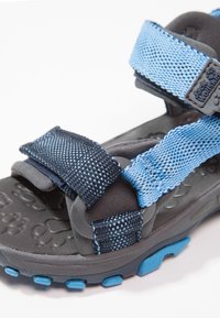 Nastavitelná sandála v tmavě šedé a nebesky modré barvě. Má síťované pásky, polstrovanou stélku a texturovanou gumovou podrážku pro lepší přilnavost.