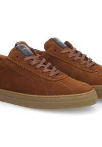 Sneaker in suede marrone con una texture sottile, dotate di lacci marroni, un accento nero e oro sulla linguetta e una suola in gomma color caramello.