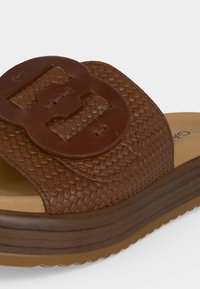 Sandale mule en cuir tressé marron avec une grande boucle sur la large bride et une semelle épaisse et rembourrée.