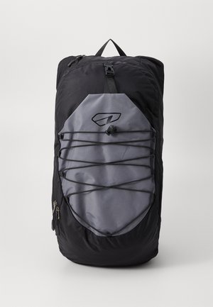 Sort og grå rygsæk med elastisk snor foran og spænde, stående oprejst mod en ensfarvet baggrund.